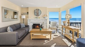 A living room with a fireplace, a sofa, a coffee table, and a view of the ocean. - 1317 S Pacific - Unit C (Oceanside)