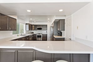 Una cocina moderna con armarios oscuros, electrodomésticos de acero inoxidable y una isla grande.