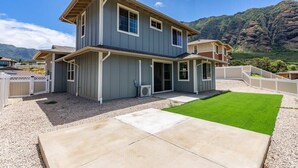 Une maison à deux étages dotée d’un patio couvert et d’une pelouse bien entretenue.