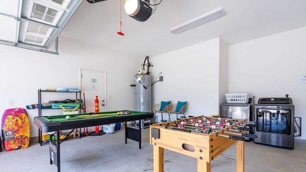 Une pièce équipée d’un baby-foot, d’une table de billard, d’un chauffe-eau et d’un lave-linge.