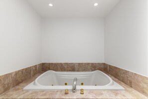 Une salle de bain moderne avec une baignoire sur pieds, des murs recouverts de carreaux de marbre et des spots encastrés au plafond.