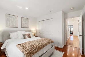 A bedroom with a large bed, a nightstand, a lamp, and two abstract paintings on the wall. - @ Marbella Lane - Vibrant 5BR Home in Daly City (Daly City)
