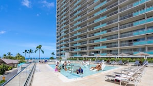 A hotel pool area with multiple levels of balconies, a pool, and lounge chairs. - @ Marbella Lane Dreamy Sunset Views by the Sea (Honolulu)