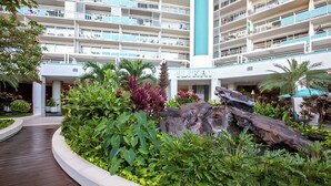 A hotel with multiple balconies, lush greenery, and a central water feature. - @ Marbella Lane Dreamy Sunset Views by the Sea (Honolulu)