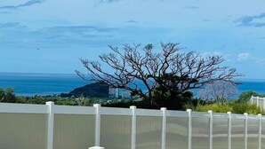 A view from a master bedroom overlooking a coastal landscape with a tree and a distant mountain. - @ML Ocean View, Golf, Gazebo and Bbq, we Have All! (Waianae)