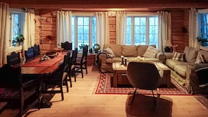 L’intérieur d’un chalet confortable, avec une salle à manger, un canapé et une table basse.