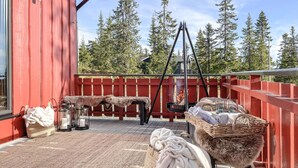 Un patio al aire libre con una cerca de madera roja, una parrilla metálica y una cesta de mimbre con objetos.