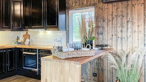 Una cocina con armarios de madera oscura, encimera de madera y una ventana con plantas.
