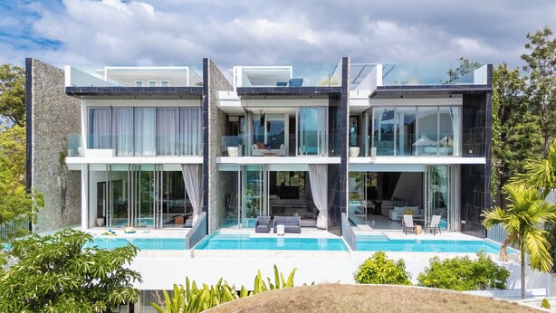 A modern two-story house with a large glass facade, a swimming pool, and a landscaped garden. - Sea Theatre Kata (Karon)