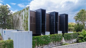 Un bâtiment moderne à la façade vitrée, entouré de verdure et d’arbres.
