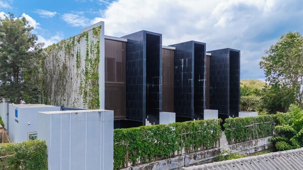 A modern building with a glass facade, surrounded by greenery and trees. - Sea Theatre Kata (Karon)
