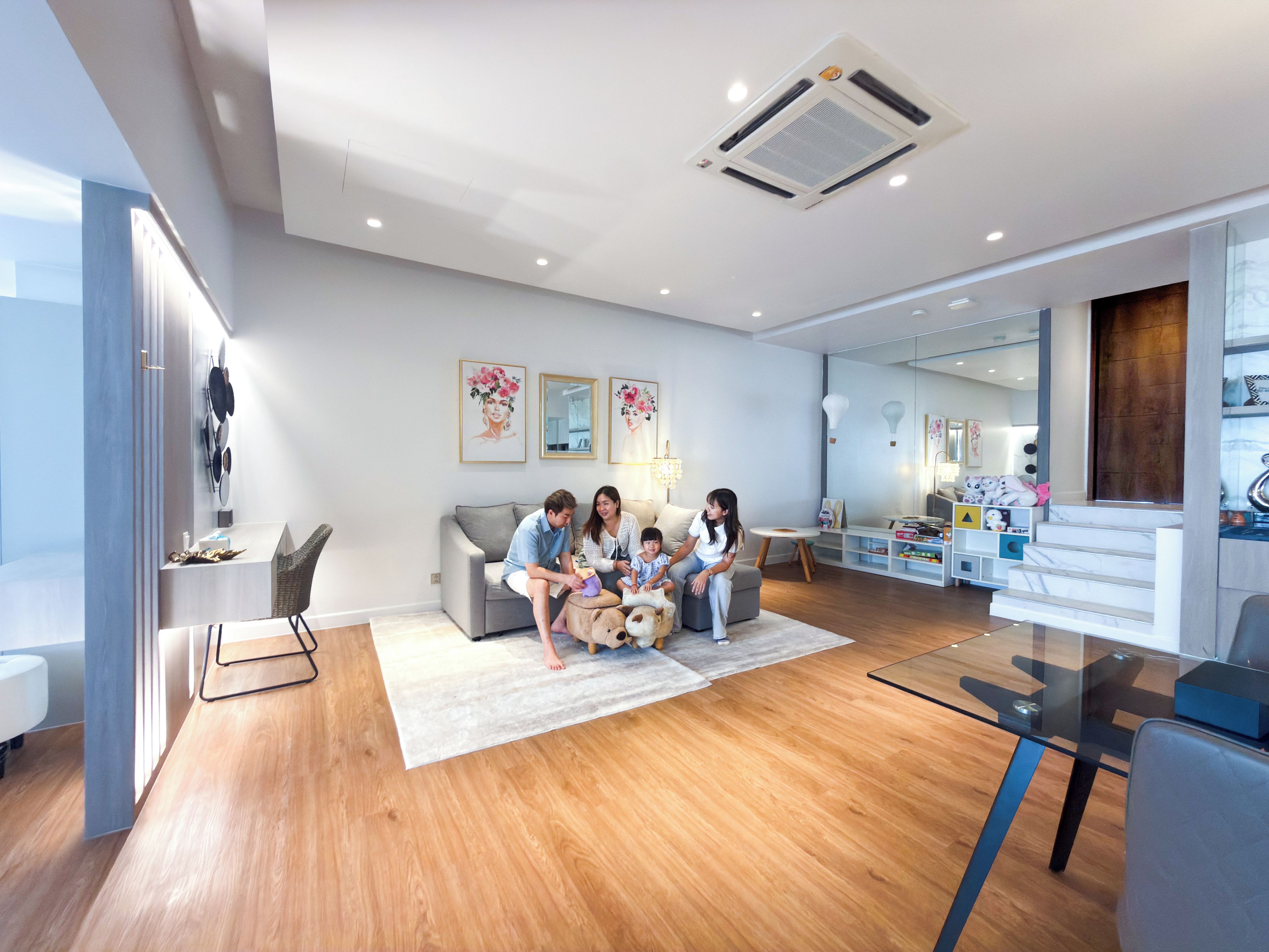A modern living room with a grey sofa, a glass coffee table, and a wooden floor.