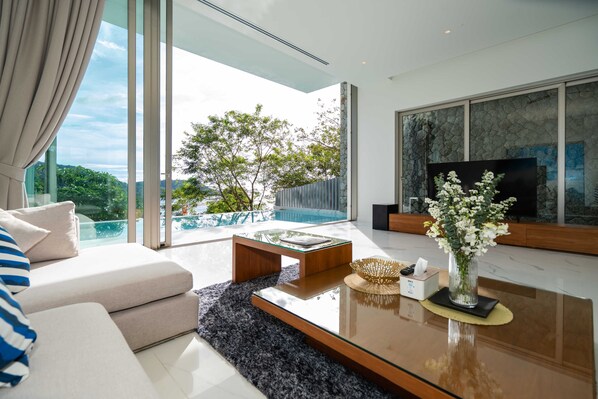 A modern living room with a glass coffee table, a sofa, and a large TV. - Sea Theatre Kata (Karon)