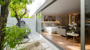 A modern bedroom with a bed, sofa, and a small table with flowers.