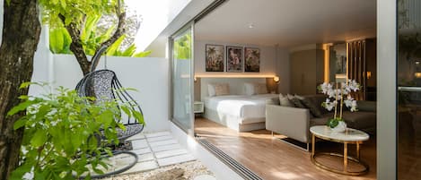 A modern bedroom with a bed, sofa, and a small table with flowers.