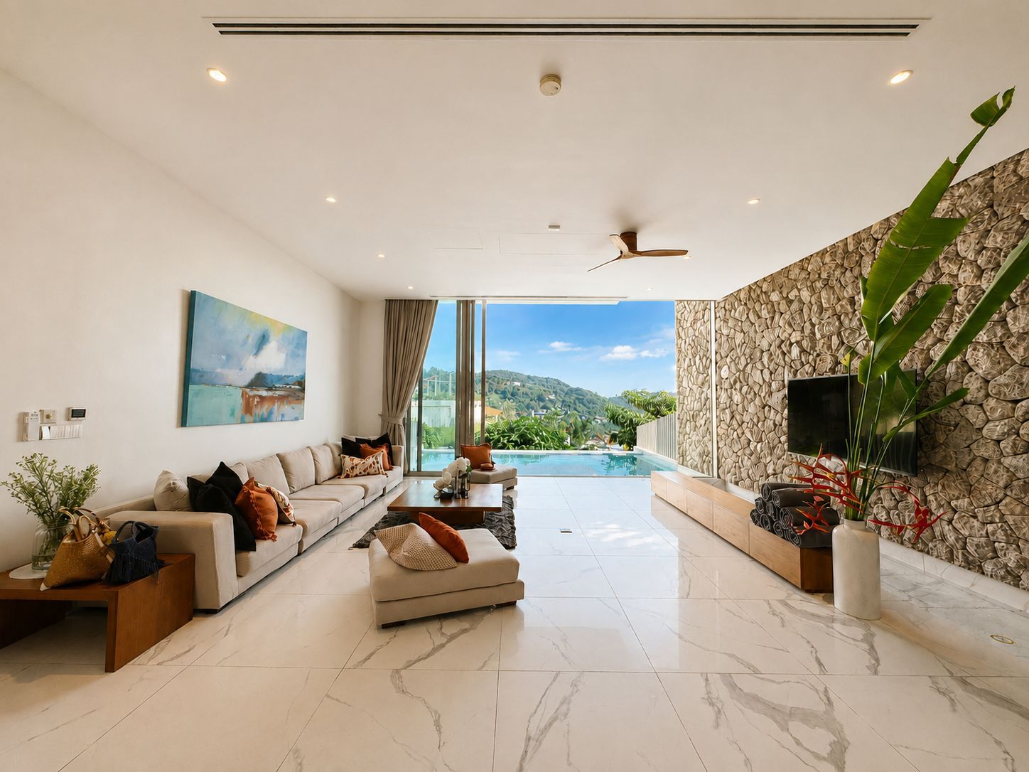 A modern living room with a sofa, coffee table, and a view of a swimming pool.