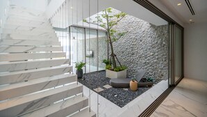 A modern interior with a marble staircase, a stone wall, and a small garden area with plants. - Sea Theatre Kata (Karon)