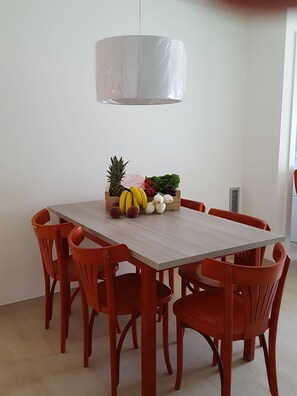 A dining table with a fruit basket, six red chairs, and a pendant light. - Mandala apARTments for those who want something mo (Calafell)
