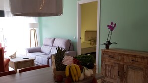 Uma sala de jantar com mesa de madeira, cadeiras vermelhas, uma cesta de frutas e um armário de madeira.