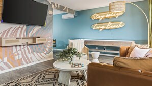 A modern living room with a TV, a neon sign, a round coffee table, and a sofa. - Vibrant 2-bedroom guest house with AC in Long Beach near Retro Row (Long Beach)