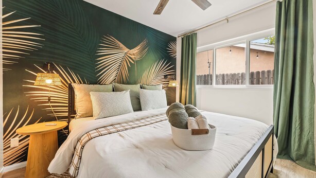 A bedroom with a bed, bedside table, lamp, and a window with curtains. - Vibrant 2-bedroom guest house with AC in Long Beach near Retro Row (Long Beach)