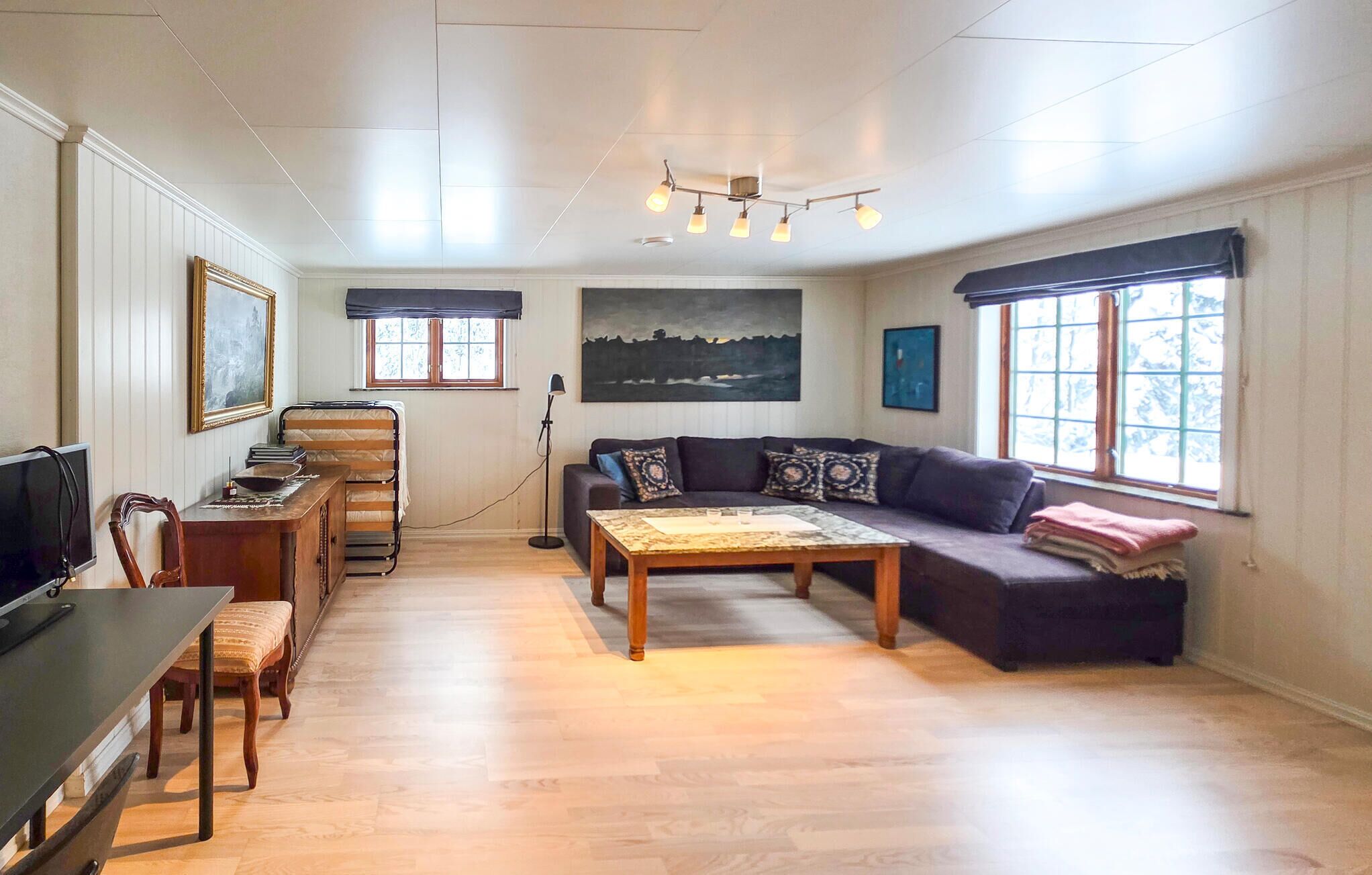Ein Wohnzimmer mit einer Couch, einem Couchtisch, einem Fernseher und einem Schreibtisch mit Stuhl.