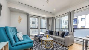 Een moderne woonkamer met een blauwgroene bank, een grijze bank en een ronde salontafel.