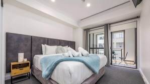 Een moderne slaapkamer met een groot bed, een nachtkastje en uitzicht op het balkon.