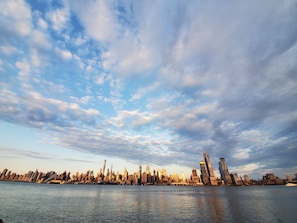 A city skyline with modern skyscrapers along a waterfront. - Duplex 15 mins from Time Square! (West New York)
