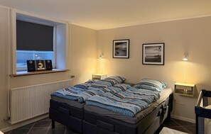 Makuuhuoneessa on sänky, kaksi yöpöytävalaisinta, ikkuna, jonka alla on patteri, sekä kaksi kehystettyä kuvaa seinällä.