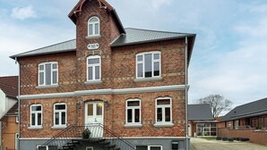 Een groot, meerlaags bakstenen gebouw met een opvallende centrale toren, meerdere ramen en een zichtbare trap.