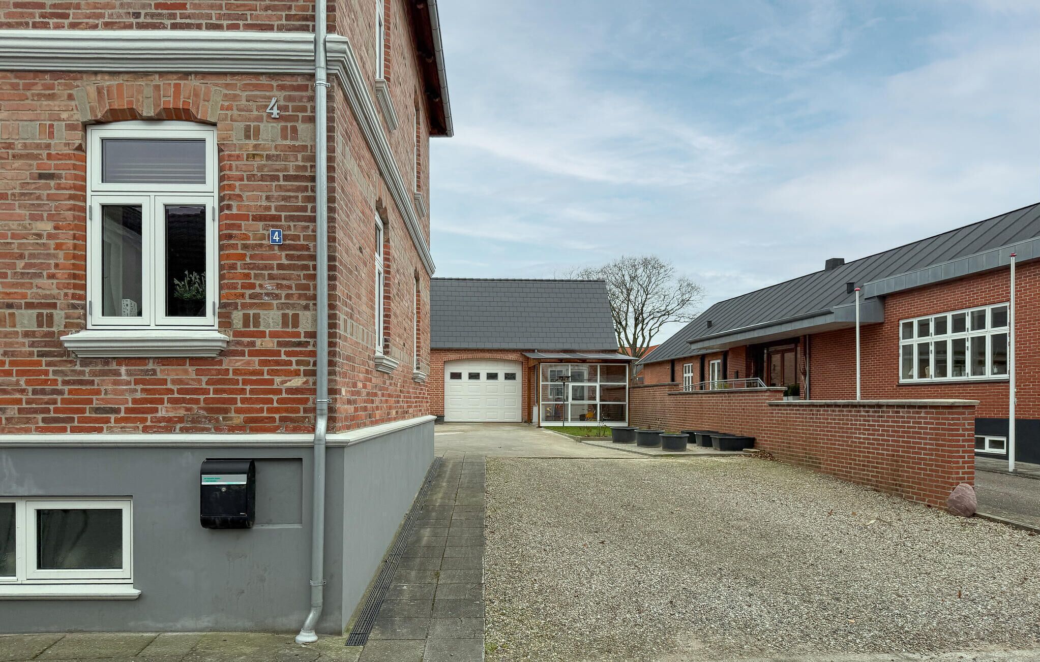 A residential building with a brick facade, a garage, and a gravel driveway.
