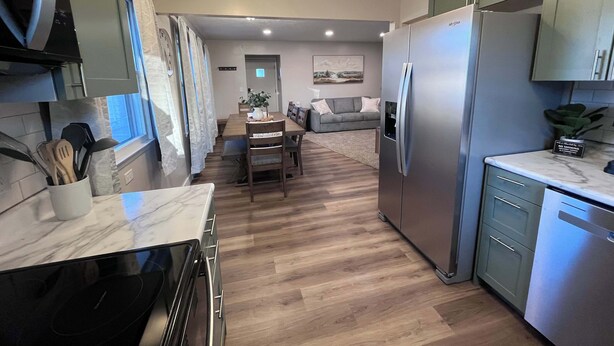 A modern kitchen with a built-in oven, a refrigerator, and a dining area with a table and chairs.