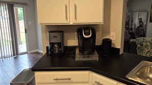 Una cocina moderna con armarios blancos, encimera negra y pileta de acero inoxidable.