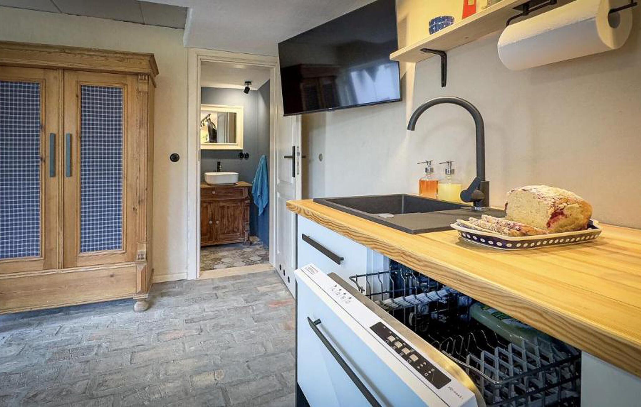 A compact kitchen with a wooden countertop, a sink, and a dishwasher.