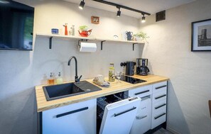 Une petite cuisine équipée d’un évier, d’une machine à café et d’un égouttoir à vaisselle.