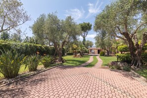 A paved pathway leading to a building with a tiled roof, surrounded by lush greenery and trees. - Dimora Patrizia, Alghero, Italy (Alghero)