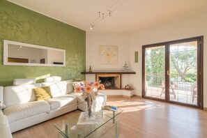 A living room with a white sofa, a glass coffee table, a fireplace, and a large window. - Dimora Patrizia, Alghero, Italy (Alghero)