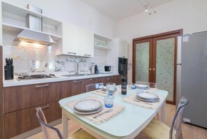 A modern kitchen with white cabinets, a gas stove, a microwave, and a refrigerator. - Dimora Patrizia, Alghero, Italy (Alghero)