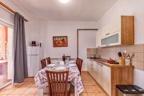 A compact kitchen with a dining table set for four, a refrigerator, and a microwave. - Pool Apt 4 - Novi Vinodolski (Ground), Novi Vinodolski, Croatia (Novi Vinodolski)