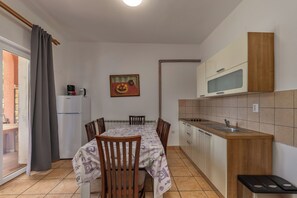 Une cuisine compacte comprenant une table à manger, des chaises, un réfrigérateur et un four à micro-ondes.