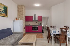 A compact living space with a kitchenette, a dining table with chairs, a sofa, and a coffee table.