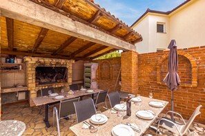 An outdoor dining area with a brick wall, a stone floor, and a wooden pergola overhead. - Pool Apt 3 - Novi Vinodolski (Ground), Novi Vinodolski, Croatia (Novi Vinodolski)