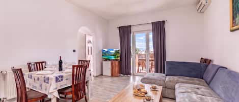 A living room with a sofa, a coffee table, and a dining area with chairs and a table set for two.