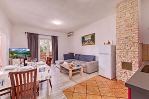 A living room with a sofa, a dining table set for two, a television, and a kitchen area with a refrigerator. - Pool Apt 3 - Novi Vinodolski (Ground), Novi Vinodolski, Croatia (Novi Vinodolski)