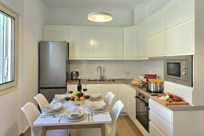 A compact kitchen with white cabinets, a stainless steel refrigerator, a microwave, and a sink. - Perla Holiday Homes 147, Lalzit Bay, Albania (Lalzit Bay)
