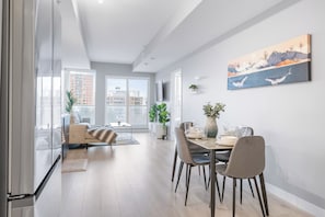A modern living room with a dining area, large windows, and a city view. - Executive King bed Suite free wifi parking (Edmonton)