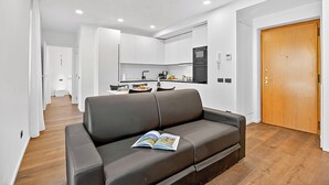 Ein modernes Wohnzimmer mit einem braunen Ledersofa, einem Buch darauf und Holzboden.