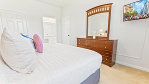 A bedroom with a bed, a dresser, a mirror, and a wall-mounted picture. - Spd2304-205 (Kissimmee)