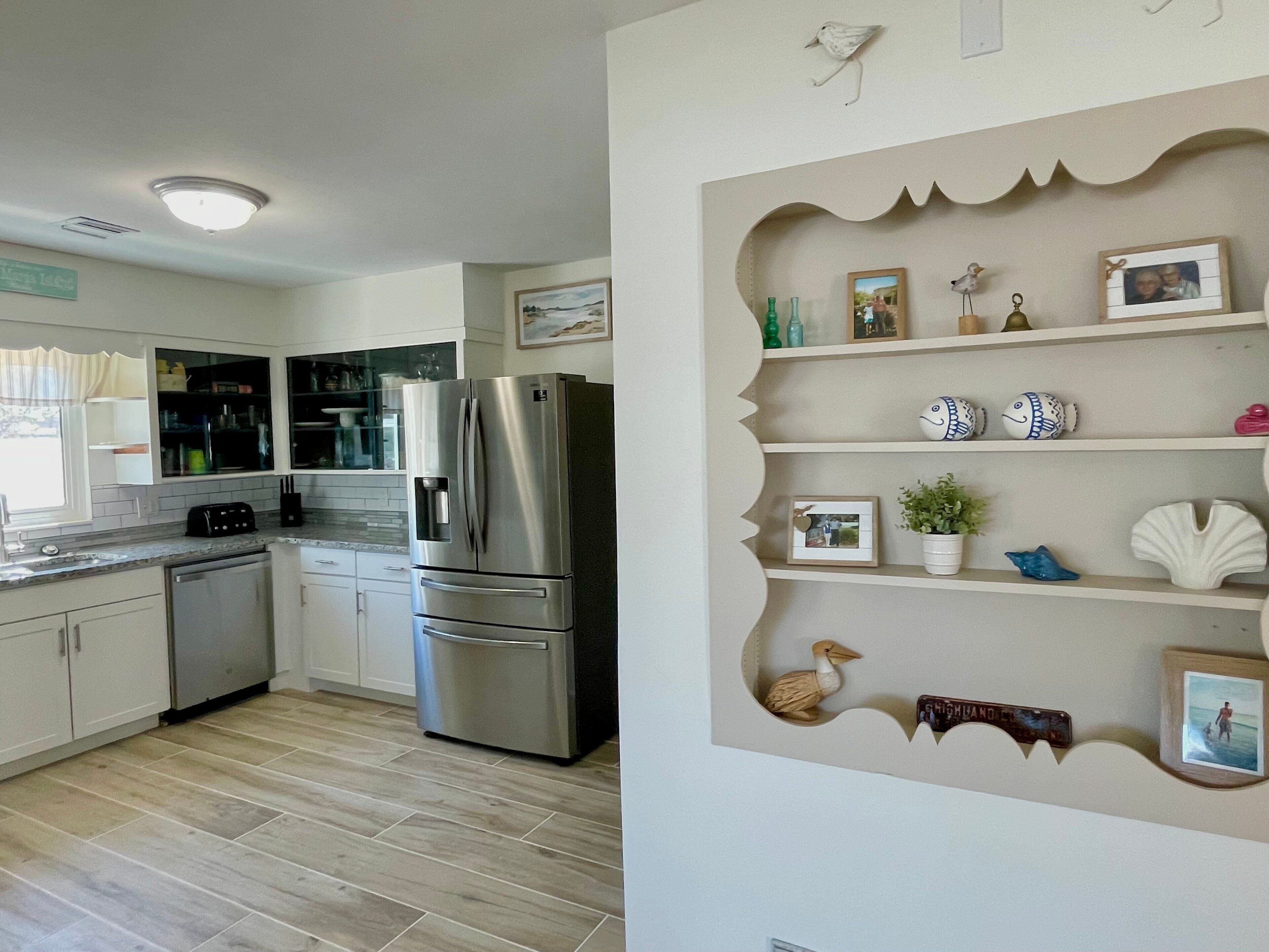 A kitchen with a stainless steel refrigerator, wooden cabinets, and a tiled floor.